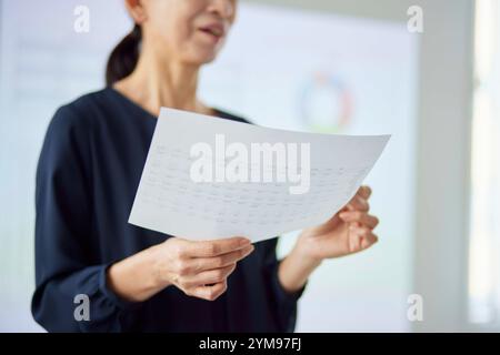 Donna giapponese anziana che fa una presentazione in ufficio Foto Stock