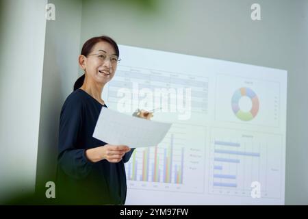 Donna giapponese anziana che fa una presentazione in ufficio Foto Stock