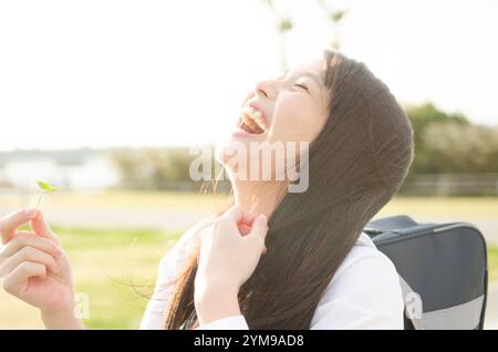 Studentessa che ride tenendo il trifoglio Foto Stock