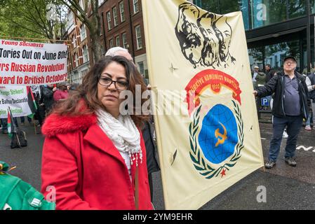 Londra, Regno Unito. 1 maggio 2017. Sa Woman in un cappotto rosso si trova accanto allo striscione del Partito Comunista turco mentre le persone che celebrano la giornata Internazionale dei lavoratori, tra cui molte comunità internazionali e migranti di Londra, si riuniscono a Clerkenwell Green prima di marciare attraverso Londra per un raduno a Trafalgar Square. Essi celebrano i numerosi risultati della lotta dei lavoratori nel corso degli anni e dimostrano la loro determinazione a combattere i tentativi di ridurre i diritti dei lavoratori e a continuare la lotta per l'uguaglianza e la giustizia. Foto Stock