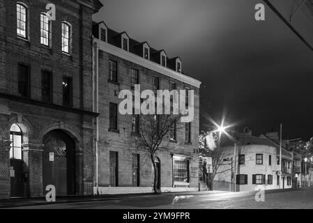 Il sobborgo The Rocks di Sydney, insediato durante la colonizzazione nel 1788, contiene molti monumenti storici ed è il più antico sobborgo dell'Australia. I suoi edifici, le scale e gli archi furono costruiti con arenaria locale, da cui il nome della zona. Fino agli anni '1870 era uno slum dove le "bande di rasoi" si riversavano di notte in vicoli. Oggi è un quartiere turistico ricco di storia circondato da Dawes Point, Millers Point e Barangaroo, spesso considerato parte del distretto di Rocks. Nella foto: Vista notturna degli edifici storici di Argyle Place a Millers Point in the Rocks, incluso il Lord Nelson Brewery Hotel. Foto Stock