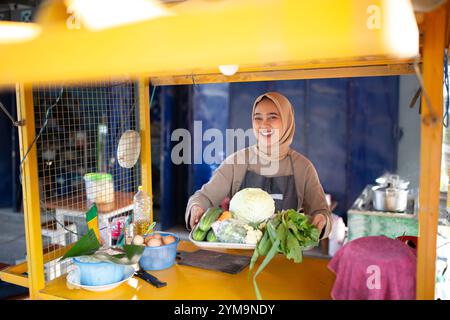 Uno stand di prodotti freschi con un venditore sorridente in un vivace ambiente di mercato Foto Stock