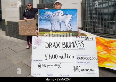 Londra, Regno Unito. 13 aprile 2017. Gli attivisti ambientali di Biofuelwatch e Axe Drax protestano fuori dagli uffici di Schroders e Invesco, i principali azionisti di Drax, la centrale elettrica più grande e inquinante del Regno Unito&#8217. Un assegno gigante di 600 milioni di sterline sottolinea che Drax riceve un enorme sussidio giornaliero di 1,5 milioni di sterline dalle nostre bollette elettriche destinate a finanziare energia rinnovabile pulita, nonostante studi scientifici dimostrino che bruciare legno è disastroso per l'ambiente, producendo grandi quantità di anidride carbonica quando bruciato ed eliminando per molti anni la capacità delle foreste che vengono abbattute per assorbire Foto Stock