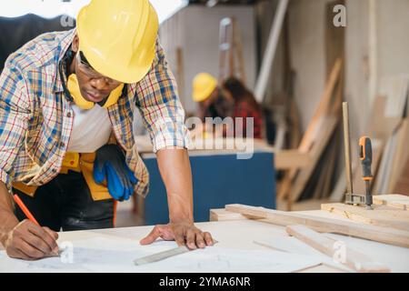 Falegname che disegna piani in legno su una scrivania. costruttori e ingegneri che progettano Foto Stock