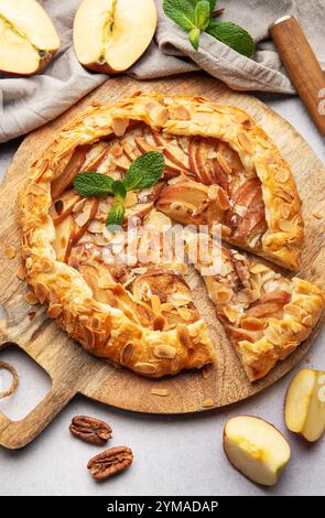 galette di mele appena sfornata, decorata con scaglie di mandorle e foglie di menta, servita su una tavola di legno Foto Stock