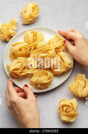 Chef donna che prepara i nidi di pasta su un piatto bianco per cucinare la cucina italiana Foto Stock