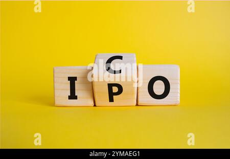 Simbolo ICO e IPO. Cubi di legno con parole ICO - offerta iniziale di monete e IPO - offerta pubblica iniziale. Bellissimo sfondo giallo. Business Conce Foto Stock