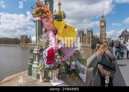 Aprile. Dieci giorni dopo l'attacco terroristico di Westminster, la gente si ferma ancora per guardare e fotografare i fiori delle vittime intorno agli standard delle lampade sul Waterloo Bridge. Foto Stock