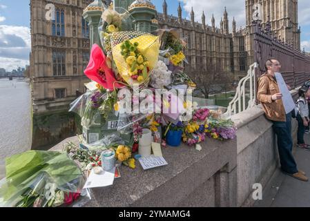 Aprile. Dieci giorni dopo l'attacco terroristico di Westminster, la gente si ferma ancora per guardare e fotografare i fiori delle vittime intorno agli standard delle lampade sul Waterloo Bridge. Foto Stock