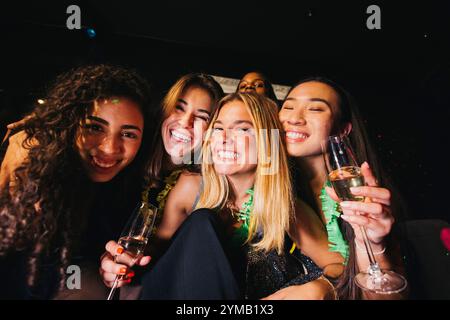 Un gruppo di amici gioiosi che si godono una serata fuori, festeggiando a una festa con bicchieri di champagne. Sorridono e abbracciano, catturando un momento Foto Stock