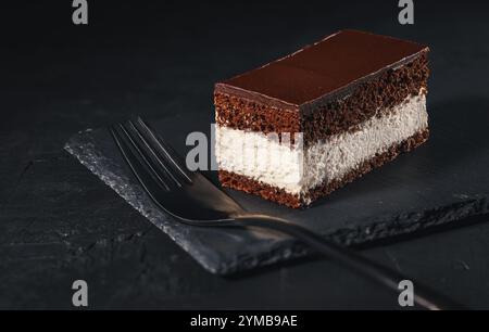 Torta al cioccolato, dolce cremoso a strati di cacao su un piatto di ardesia con fondo scuro Foto Stock