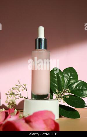 Una bottiglia di lozione di siero facciale con estratto di rose su podio bianco e sfondo rosa beige Foto Stock