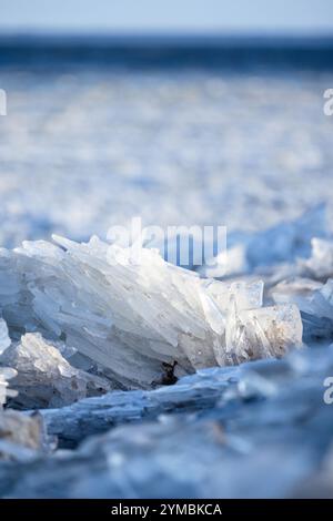 Il ghiaccio taglia la foto in primo piano con una messa a fuoco morbida selettiva e ghiaccio congelato su sfondo blu sfocato e foto verticale Foto Stock