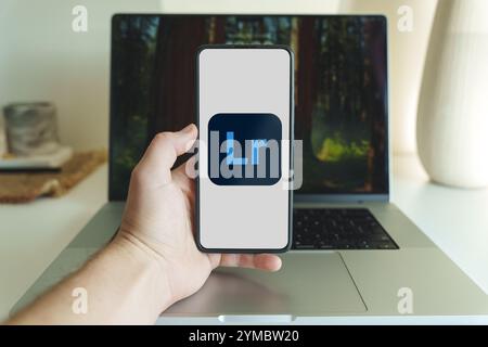 Logo dell'applicazione di editing di foto Adobe Lightroom sullo schermo dello smartphone davanti al laptop. Vilnius Lituania - 2024 20 novembre. Foto di alta qualità Foto Stock
