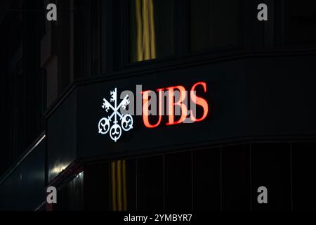 18-11-2024, Zurigo, Svizzera. Grande logo rosso della banca UBS sul fronte dell'edificio di notte. Illuminato, scena oscura, primo piano, nessuna gente Foto Stock