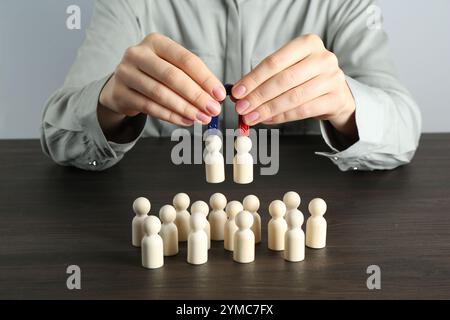 Donna con magnete che attrae figure umane al tavolo di legno, primo piano Foto Stock