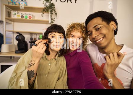 Tre amici multietnici che applicano il trucco e si divertono Foto Stock