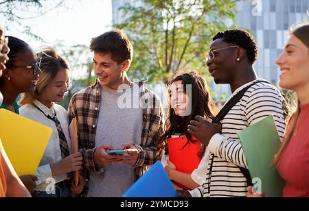 Amici studenti multirazziali riuniti dopo la lezione, parlando e divertendosi insieme fuori dall'università Foto Stock