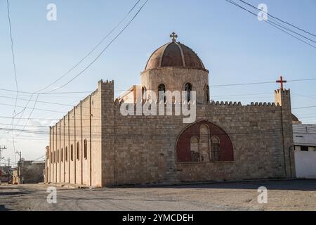 Una vista generale di un vicolo vuoto mostra la Chiesa caldea del Sacro cuore di Gesù nella città di Tel Keppe (Tel Kaif) a nord della città di Mosul, in Iraq, durante un coprifuoco di due giorni iniziato oggi con un censimento della popolazione nazionale. Questa settimana l'Iraq sta tenendo il suo primo censimento nazionale in quasi quattro decenni, un conteggio atteso da tempo in una nazione che le divisioni settarie ed etniche hanno rovinato. Durante il censimento opererà un coprifuoco di due giorni, con le famiglie che devono rimanere a casa in modo che 120.000 ricercatori possano raccogliere dati direttamente dalle famiglie. Foto Stock