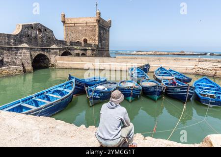 In un bacino riparato del porto peschereccio di Essaouira, alcune piccole imbarcazioni da pesca, di un blu intenso, riposano dopo aver messo in mare Foto Stock