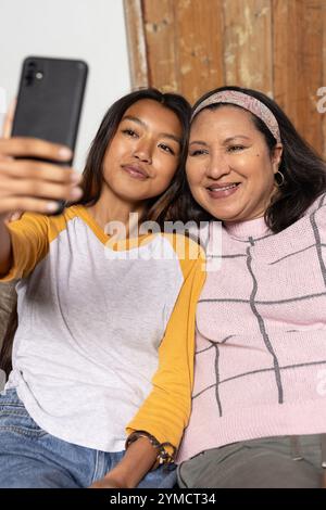 la ragazza asiatica adolescente e la nonna scattano selfie insieme a casa, condividendo momenti di gioia Foto Stock