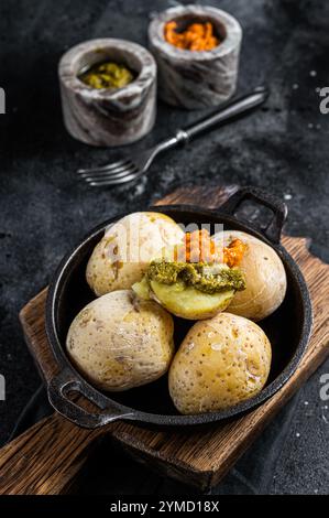 Papas arrugadas Isole Canarie patate rugose con salse verdi e rosse servite in una padella. Sfondo nero. Vista dall'alto. Foto Stock