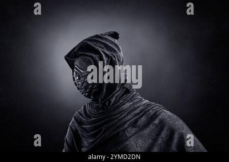 Figura spaventosa in mantello con cappuccio con borchie a spillo di notte su sfondo scuro nebbioso Foto Stock