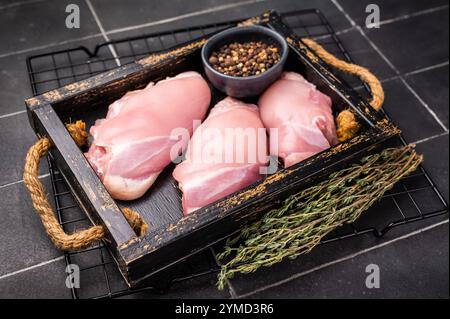 Filetti di cosce di pollo crude in un vassoio di legno fondo nero. vista dall'alto. Foto Stock