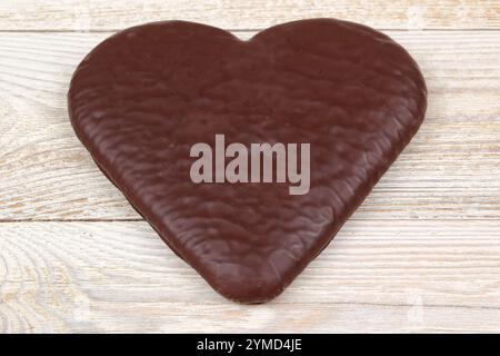 Il delizioso cioccolato a forma di cuore è posizionato splendidamente su un ricco sfondo in legno Foto Stock