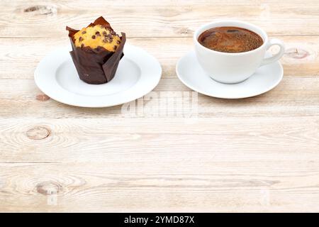 Assapora un delizioso muffin accompagnato da caffè appena preparato su un tavolo in legno rustico Foto Stock