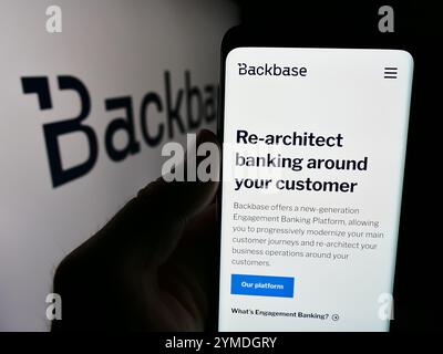 In questa immagine, una persona ha in mano uno smartphone con la pagina Web della società olandese di tecnologia fintech Backbase B.V. davanti al logo aziendale. Foto Stock