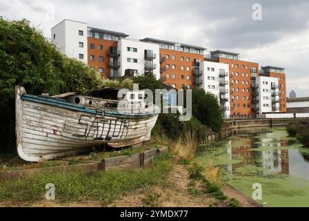 East London, la valle della bassa Lea, sede dei Giochi Olimpici di Londra del 2012, 4 agosto 2006. Sailor, noto anche come Voodoo Chile, una barca abbandonata sul sentiero cittadino del fiume Mill, che prende il nome dalla canzone Voodoo Chile. One Canada Square, edificio di uffici a torre, Canary Wharf in lontananza. 2000 UK HOMER SYKES Foto Stock