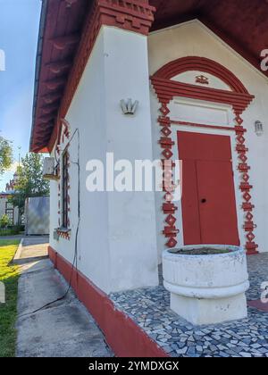 edificio pittoresco con una porta rossa e intricati mattoni, adornato da una piantatrice all'entrata. La facciata mescola fascino rustico con tradizionale Foto Stock