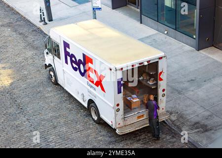 Il furgone FedEx Express è parcheggiato su una strada della città con vetrine e viene scaricato Foto Stock