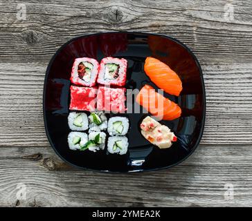 vari sushi su piatto nero su sfondo di legno Foto Stock