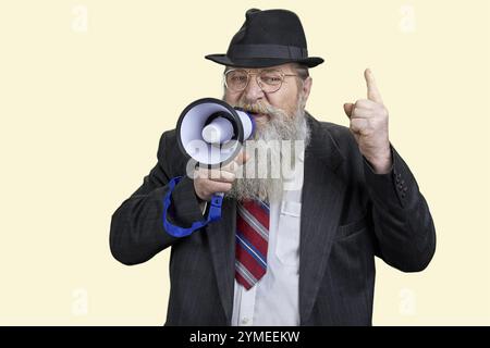 Ritratto di un uomo d'affari anziano che tiene un discorso in megafono. Sfondo giallo pastello Foto Stock