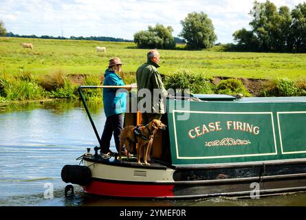 CAMBRIDGESHIRE, Regno Unito - 18 AGOSTO 2017: Coppia con cane che viaggia su una barca stretta tradizionale lungo il fiume Great Ouse. Le vacanze in barca sono molto popolari Foto Stock