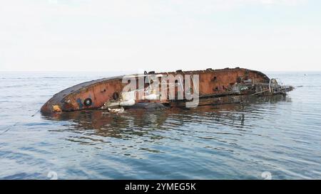 Vista dal drone che sorvola da vicino la nave petroliera arrugginita rotta. Vecchia petroliera rovesciata e arrugginita giacente sul bordo in acque poco profonde Foto Stock