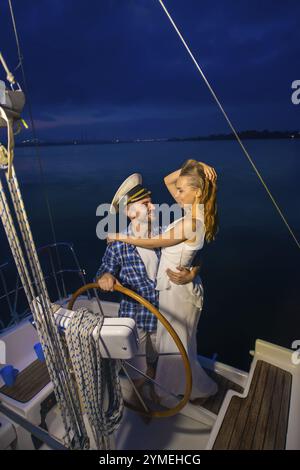 Gita romantica su uno yacht. Passeggiata notturna lungo il fiume. Coppia amorevole su uno yacht. Luna di miele sullo yacht Foto Stock