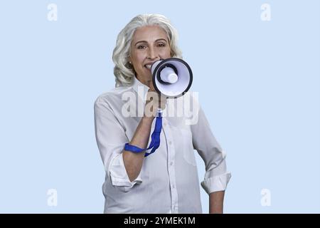 Ritratto di donna anziana positiva con megafono. Isolato su sfondo rosa Foto Stock