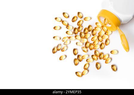 Pila di capsule gialle softgel Omega 3 con olio di pesce sminuzzato da una bottiglia bianca isolata su sfondo bianco. Assistenza sanitaria, concetto di stile di vita sano. Superiore Foto Stock