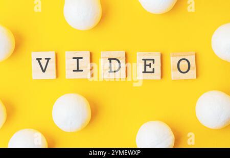 Sfondo giallo con lettere bianche che scrivono la parola video in un carattere di blocco di legno. L'immagine è un modo creativo per scrivere la parola video utilizzando Foto Stock