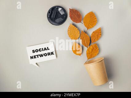 Segno bianco con la parola social network scritta sopra. Una pianta a foglia è posta in un bicchiere di carta marrone Foto Stock
