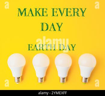 Quattro lampadine su sfondo giallo con le parole fanno ogni giorno della Terra. Concetto di promozione della consapevolezza ambientale Foto Stock