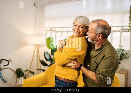 Felice coppia anziana che balla insieme nel soggiorno Foto Stock