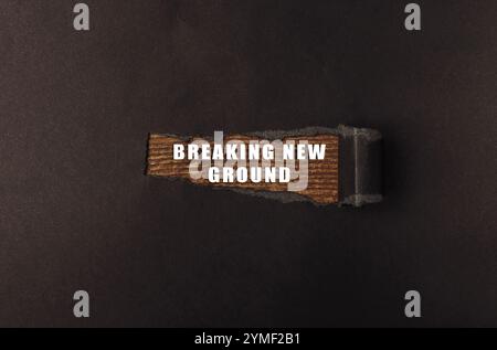Cartello di legno che dice "Breaking New Ground". Il segnale è diviso a metà ed è su uno sfondo nero Foto Stock