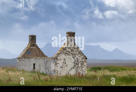 Moine House, una casa abbandonata sul Flow, lungo la costa settentrionale della Scozia, con Ben Loyal visibile in lontananza, attraverso le nuvole di tempesta. Scott Foto Stock