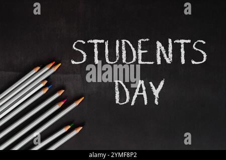 Il giorno degli studenti è scritto su una lavagna con un mucchio di matite sopra. Le matite sono disposte in fila e sono di colori diversi Foto Stock