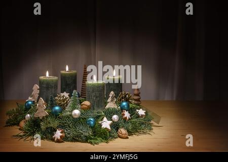 Corona dell'Avvento con candele verde scuro, la quarta è illuminata, decorazione natalizia, baubles, noci e stelle di cannella, tavolo in legno, decorazione natalizia, co Foto Stock