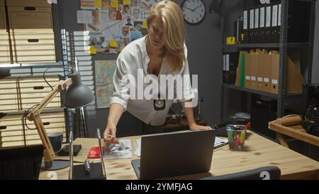 Una detective bionda esamina le prove in un ufficio ben organizzato della stazione di polizia. Foto Stock